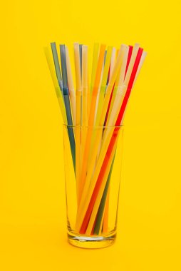 Sarı arka planda pipet içen camın yakın plan görüntüsü