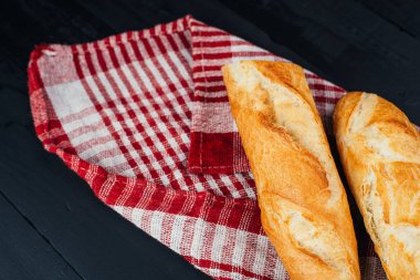 Lezzetli ev yapımı baget ekmeğin ve ahşap arka planda kareli havlunun yakın plan görüntüsü.