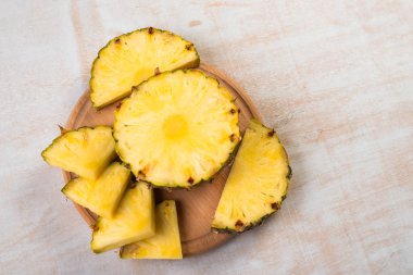 Ahşap tahtada açık arkaplanda taze kesilmiş ananasın üst görüntüsü  