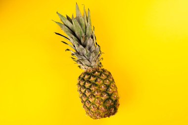 Sarı arka planda olgun, tek bir ananas..