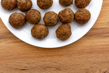 top view of delicious cooked meatballs on round white plate on wooden table