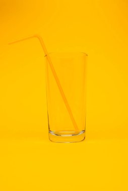 Sarı arka planda pipet içen camın yakın plan görüntüsü