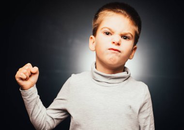 Saldırgan çocuk gri arka plandaki kameraya bakıyor. 