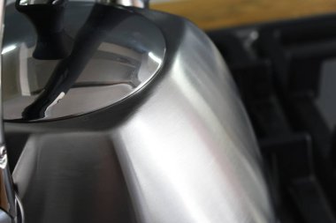 close-up view of shiny silver kettle on stove in kitchen