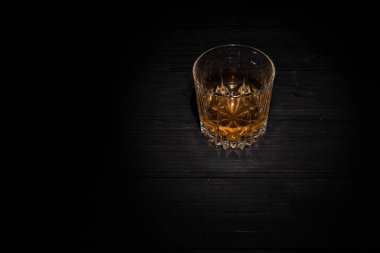 Tahta masada buz küpleri olan bir bardak viski. 