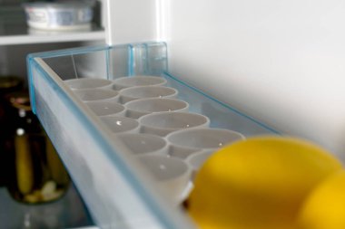 close-up view of fresh ripe lemon on shelf in refrigerator
