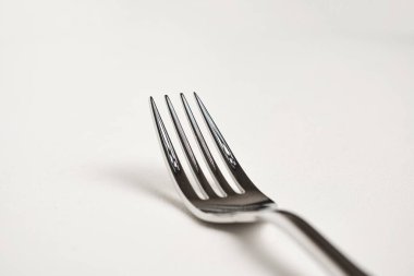 Beyaz arkaplanda parlak gümüş çatalın yakın plan görüntüsü