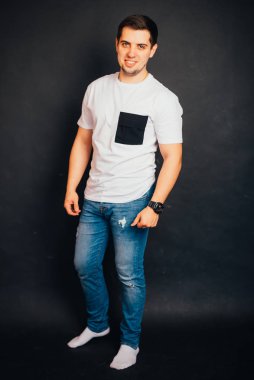 Siyah arka planda duran ve gülümseyen yakışıklı genç adam.