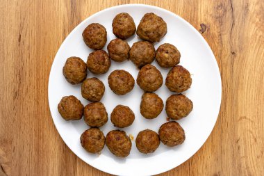 top view of delicious cooked meatballs on round white plate on wooden table