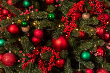 Parlak kırmızı ve yeşil takılarla süslenmiş güzel Noel ağacının yakın görüntüsü.