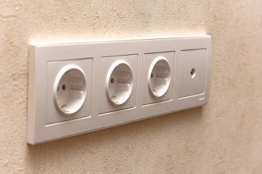 close-up view of white electric sockets on wall indoors, selective focus