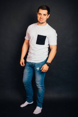 Siyah arka planda duran ve gülümseyen yakışıklı genç adam.