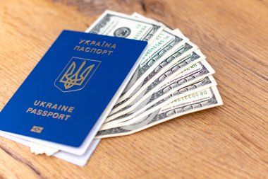 Ukrayna pasaportunun yakın plan görüntüsü ve ahşap arka planda dolar banknotları