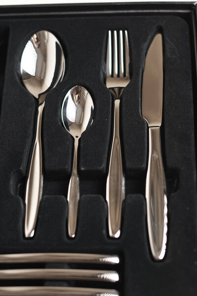 вид сверху на набор блестящих столовых приборов в черном контейнере
 