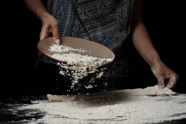 黒を背景に小麦粉をふるいにかけ生地を調理する女性の中央部 — ストック写真