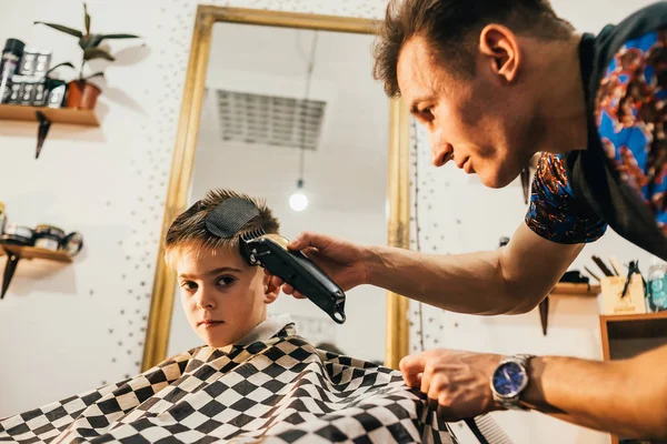 若い理容師がサロンで男の子の散髪をし — ストック写真