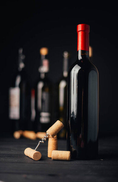 close-up view of wine bottles with corks and corkscrew on wooden surface, selective focus