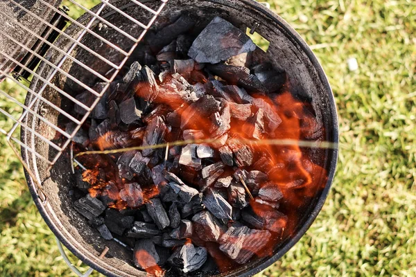 top view of charcoal grill with flame on green grass