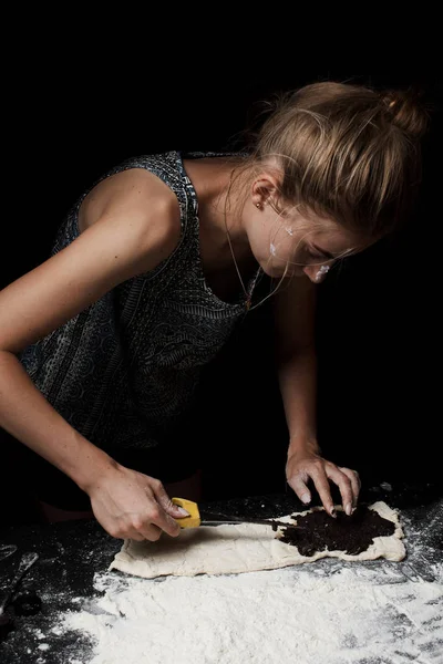 若い女性は黒を背景に甘いケシの種饅頭を調理 — ストック写真