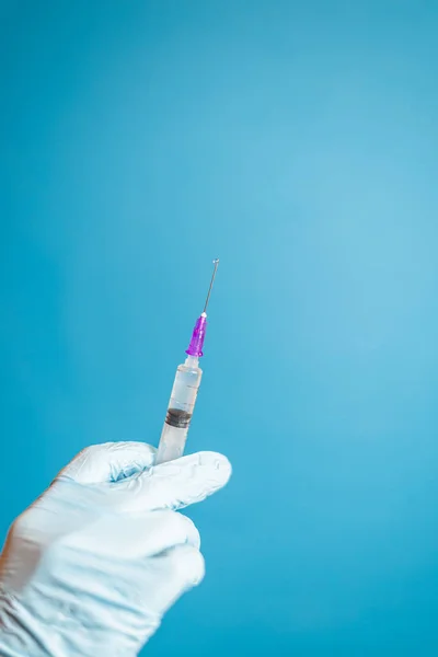 Eldivenli Doktorun Mavi Arka Planda Aşısı Olan Bir Şırınga Tutarken — Stok fotoğraf