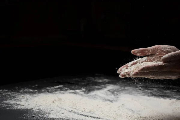 小麦粉をふるいにかけ黒い背景で生地を作る女性のクロップショット — ストック写真