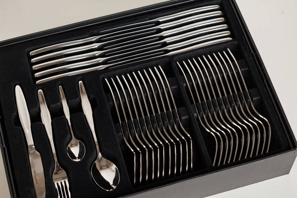 крупный план блестящих столовых приборов в черном контейнере на белом фоне
  