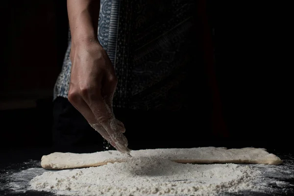 女性が小麦粉をふるい 黒を背景に新鮮な自家製生地を調理することのクローズアップ部分的なビュー — ストック写真