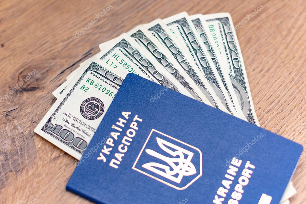 close-up view of ukrainian passport and dollar banknotes on wooden background