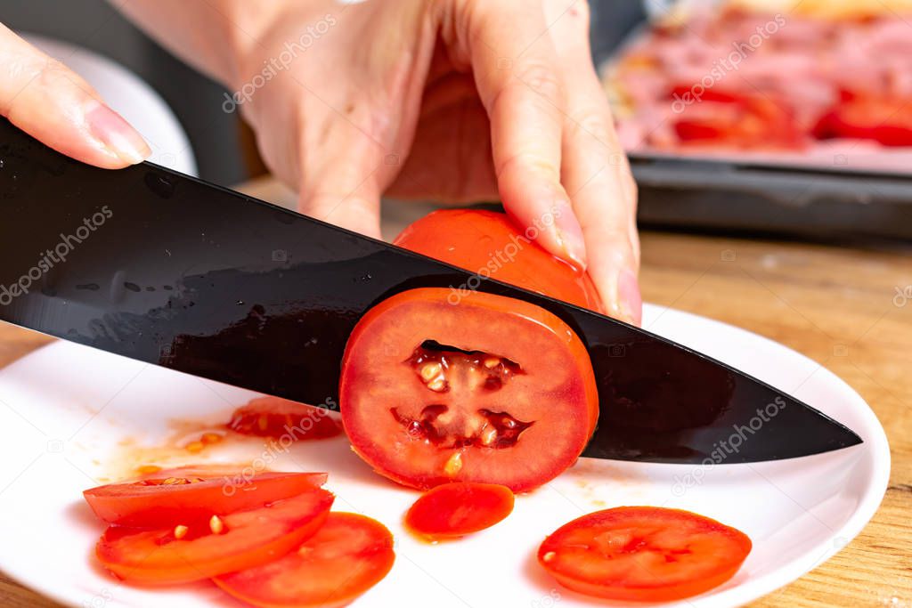 cropped shot of woman preparing pizza with tomatoes 