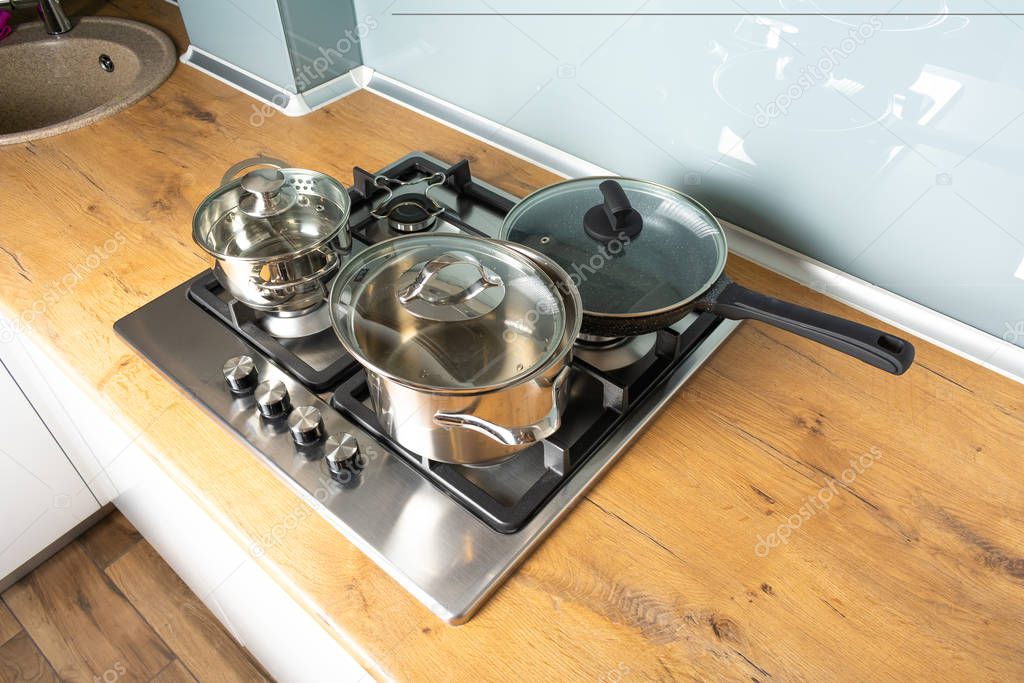 high angle view of pans on modern stove and wooden counter in kitchen 