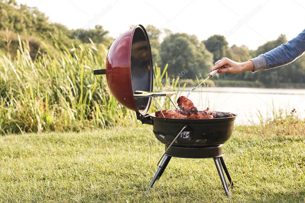 cropped shot of woman cooking delicious meat in charcoal grill outdoors