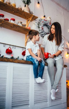 Mutlu genç bir anne ve sevimli küçük oğlu Noel 'de mutfakta birbirlerine gülümsüyorlar. 