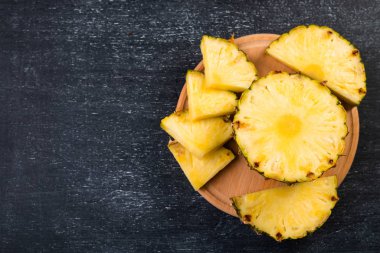Koyu arkaplanda tahta üzerinde taze dilimlenmiş ananas manzarası  