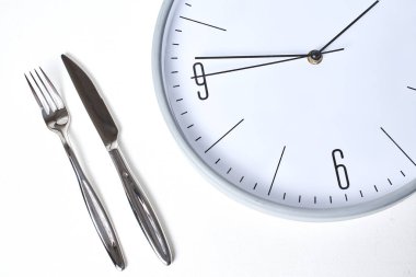 Yuvarlak saat ve çatalın beyaz zemin üzerinde bıçak ile üst görünümü  