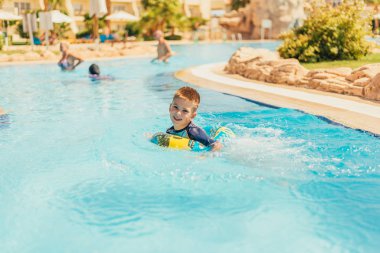 Yaz tatilinde havuzda yüzen sevimli, mutlu küçük çocuk. 