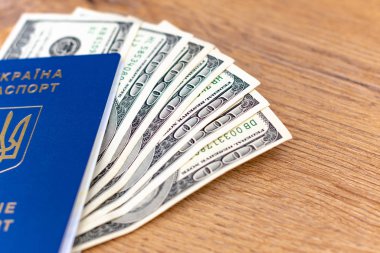 Ukrayna pasaportunun yakın plan görüntüsü ve ahşap arka planda dolar banknotları