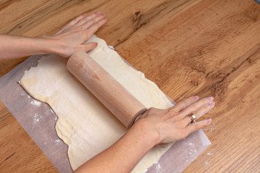 Ahşap masada hamur hazırlayan kadının kısmi görüntüsü