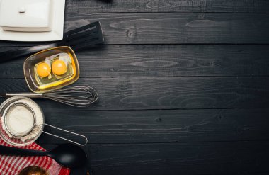 Siyah ahşap arka planda ev yapımı hamur işi için malzemeler pişiriyorum. Fırın kavramı