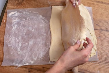 Ahşap masada hamur hazırlayan bir kadın resmi.