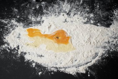 Siyah arka planda un ve çiğ yumurta hamurunun yakın plan görüntüsü.
