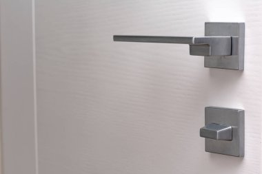close-up view of modern white door with metal handle indoors