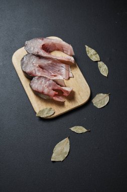 Siyah arkaplanda tahta üzerinde defne yaprakları olan balık dilimlerinin yakın plan görüntüsü  