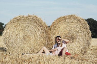 Mutlu genç çift saman balyalarının yanında yatıyor. 