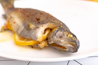 Ahşap masada servis edilen limon dilimli lezzetli fırınlanmış balığın yakın plan görüntüsü.