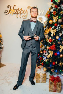 handsome man in suit with microphone near Christmas tree
