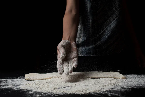 女性が小麦粉をふるい 黒を背景に新鮮な自家製生地を調理することのクローズアップ部分的なビュー — ストック写真