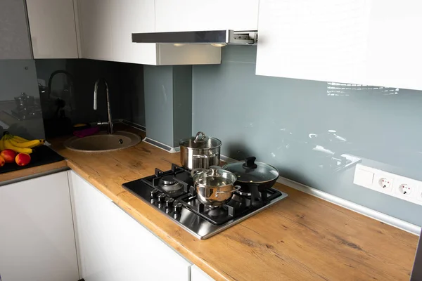 shiny pans on stove and wooden counter in modern kitchen interior