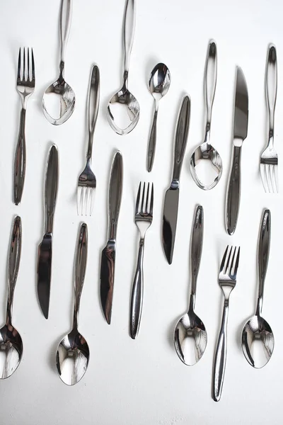 top view of forks, spoons and knives on white background