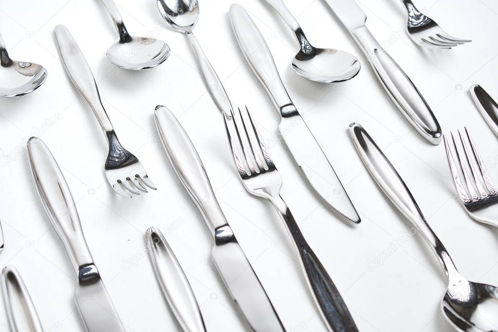 close-up view of set of shiny silver cutlery on white background