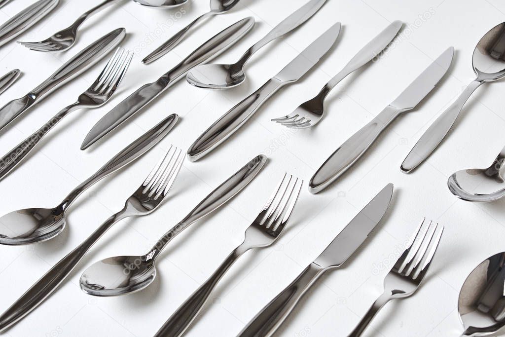 close-up view of forks, spoons and knives on white background